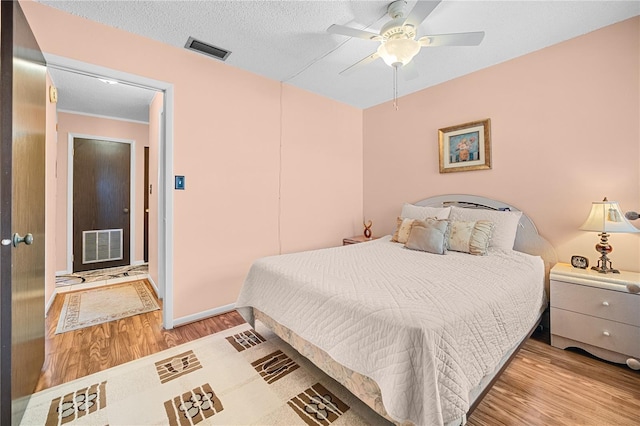 bedroom with a textured ceiling, light hardwood / wood-style floors, and ceiling fan