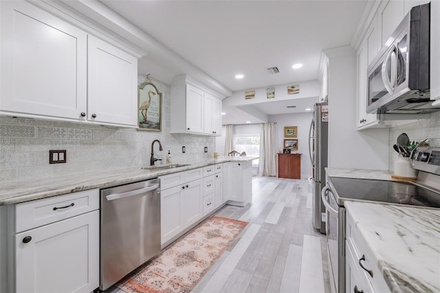 kitchen featuring light stone countertops, stainless steel appliances, sink, light hardwood / wood-style floors, and white cabinetry