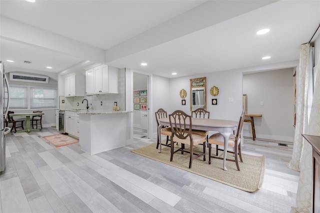 dining area featuring wine cooler, sink, and light hardwood / wood-style floors