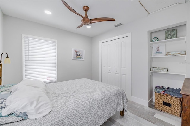 bedroom with a closet, light hardwood / wood-style flooring, and ceiling fan