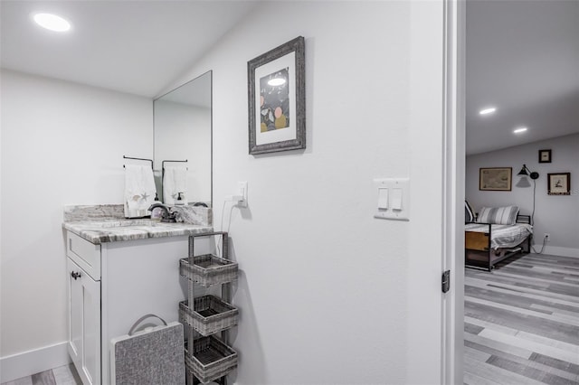 bathroom featuring hardwood / wood-style floors, vanity, and lofted ceiling