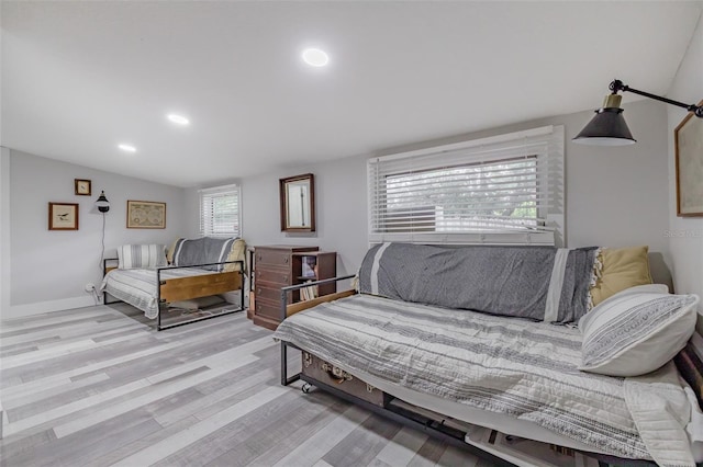 bedroom featuring light hardwood / wood-style flooring, multiple windows, and lofted ceiling