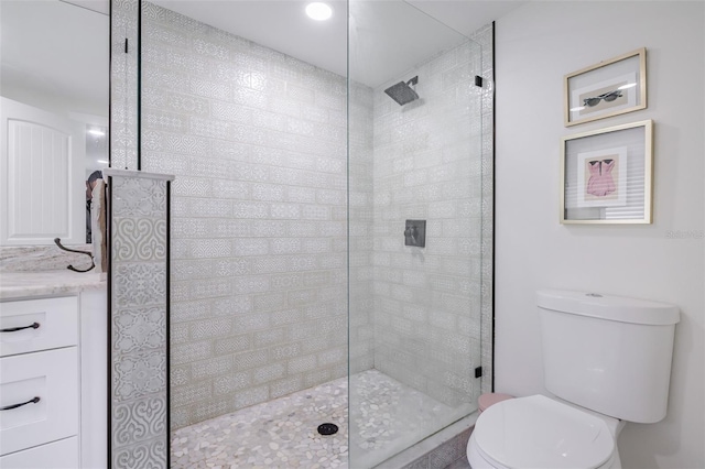 bathroom with a tile shower, vanity, and toilet