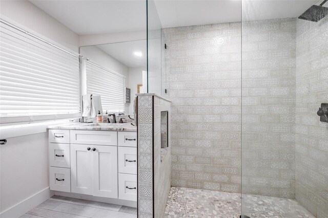 bathroom with tile patterned flooring, vanity, and a tile shower