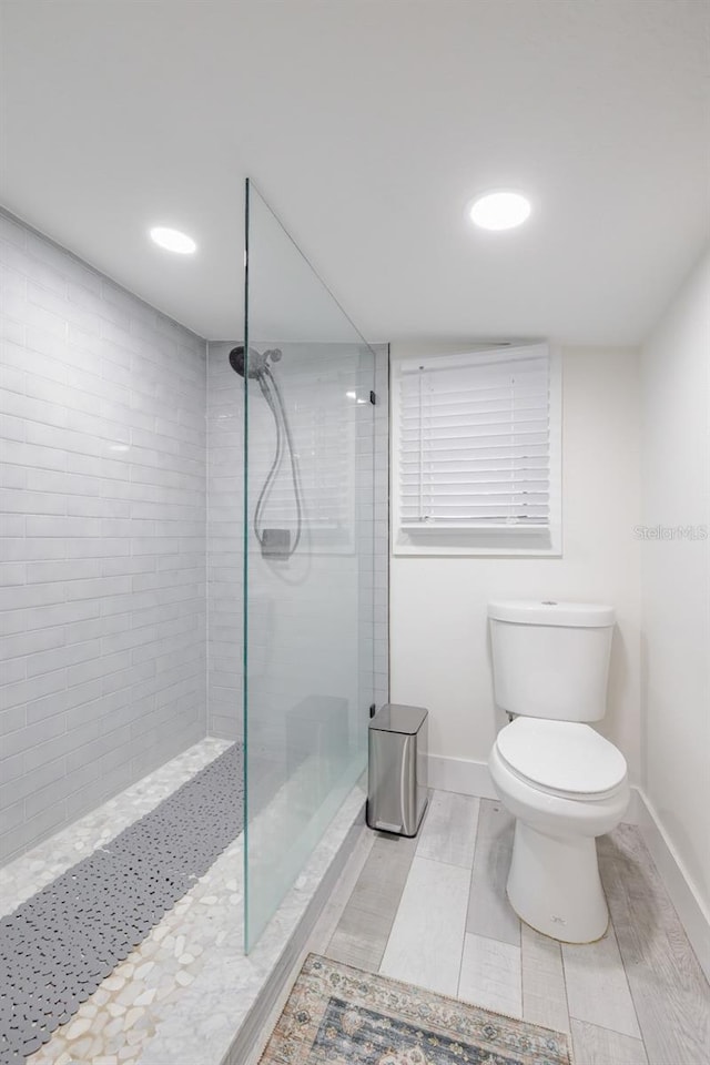 bathroom featuring a tile shower and toilet