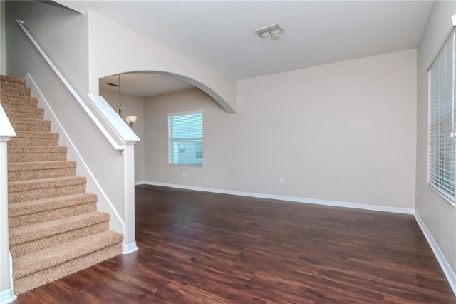 unfurnished living room with a notable chandelier and dark hardwood / wood-style floors