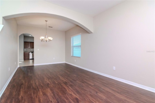 spare room with dark hardwood / wood-style floors and a chandelier