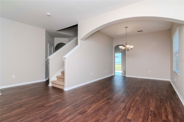 unfurnished room with a notable chandelier and dark hardwood / wood-style floors