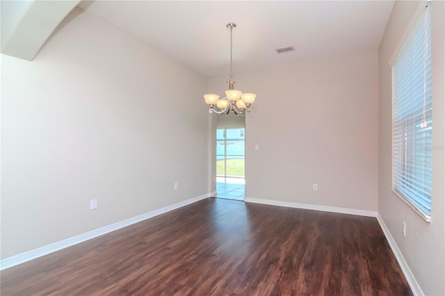 unfurnished room with dark wood-type flooring and an inviting chandelier