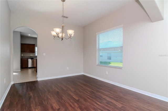 spare room with dark hardwood / wood-style flooring and a notable chandelier