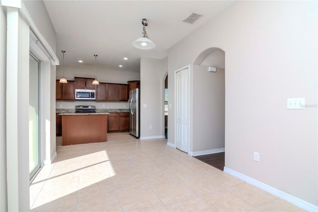 kitchen with pendant lighting, a kitchen island, light tile patterned floors, and stainless steel appliances