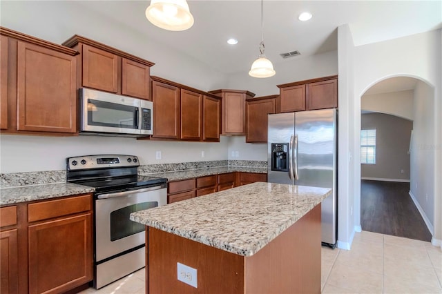 kitchen featuring light stone countertops, stainless steel appliances, decorative light fixtures, a center island, and light tile patterned flooring