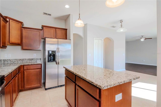 kitchen with stainless steel fridge, ceiling fan, pendant lighting, a kitchen island, and light tile patterned flooring