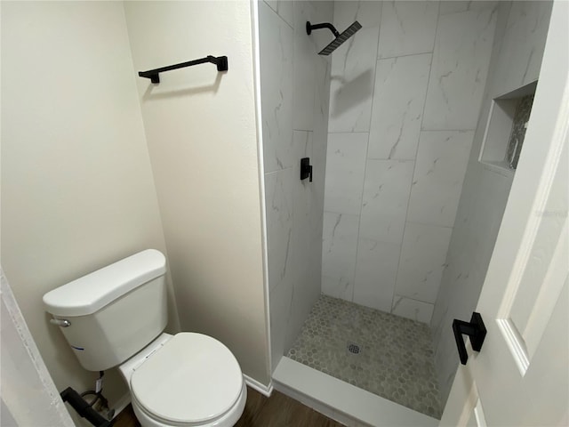 bathroom with tiled shower, hardwood / wood-style flooring, and toilet