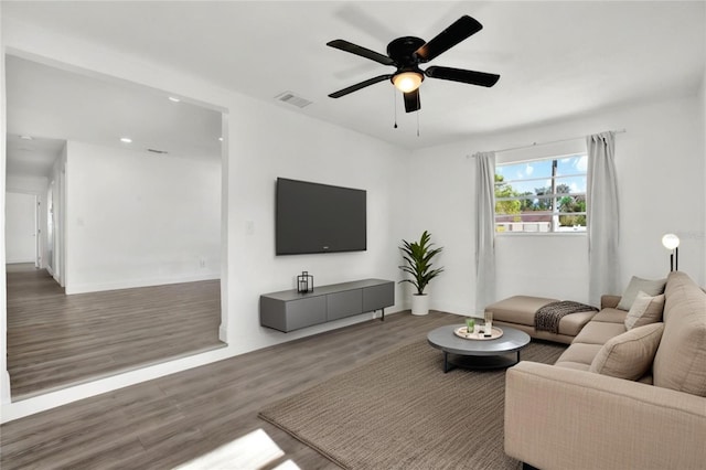 living room featuring ceiling fan and dark wood-type flooring