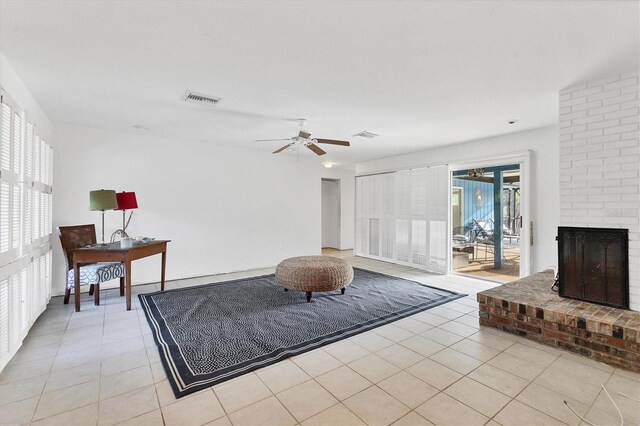 living room featuring ceiling fan, light tile patterned floors, and a brick fireplace