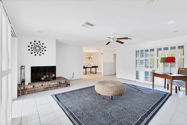 living room with a fireplace, light tile patterned floors, and ceiling fan with notable chandelier