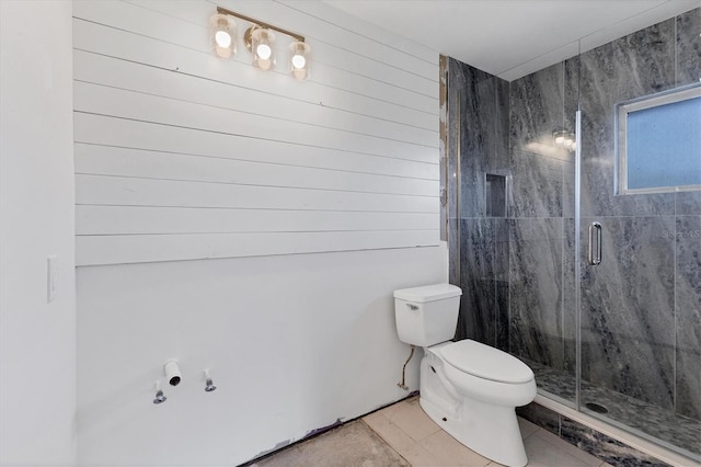 bathroom with tile patterned floors, toilet, a shower with door, and wood walls