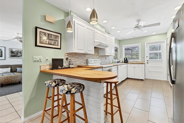 kitchen with kitchen peninsula, a kitchen bar, white electric stove, butcher block countertops, and white cabinetry