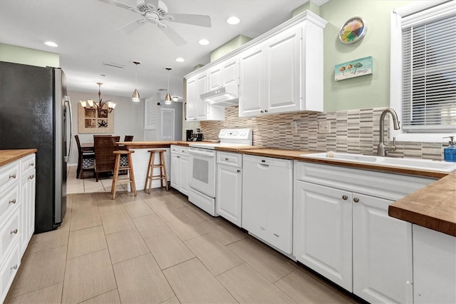 kitchen with white appliances, sink, hanging light fixtures, butcher block countertops, and white cabinetry