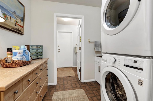 washroom with stacked washing maching and dryer and cabinets