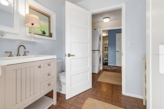 bathroom featuring vanity, toilet, and stacked washer and dryer