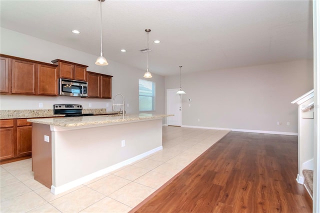 kitchen featuring a center island with sink, light tile patterned flooring, and stainless steel appliances