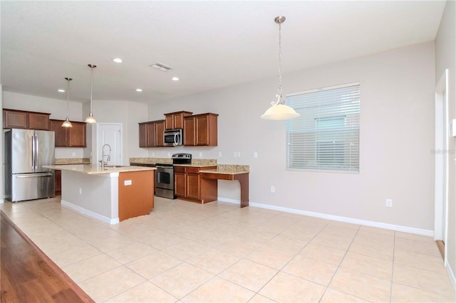 kitchen featuring pendant lighting, a center island with sink, sink, appliances with stainless steel finishes, and a kitchen bar