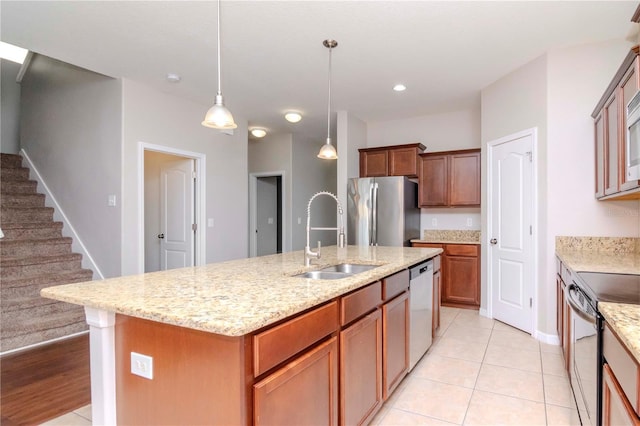 kitchen featuring stainless steel appliances, sink, light tile patterned floors, hanging light fixtures, and an island with sink