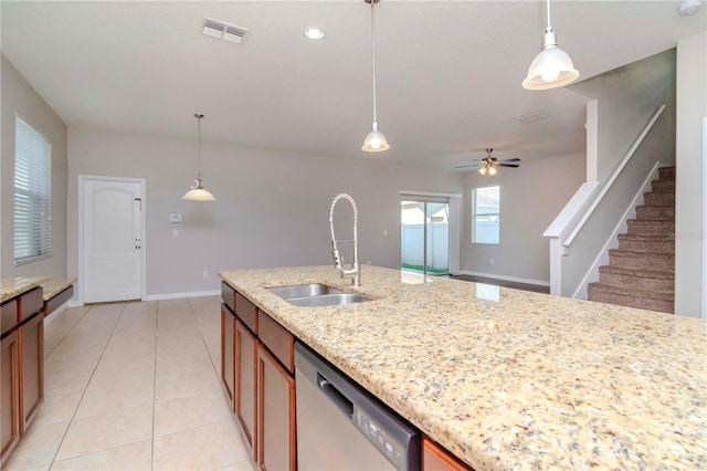 kitchen with light stone counters, stainless steel dishwasher, hanging light fixtures, and sink