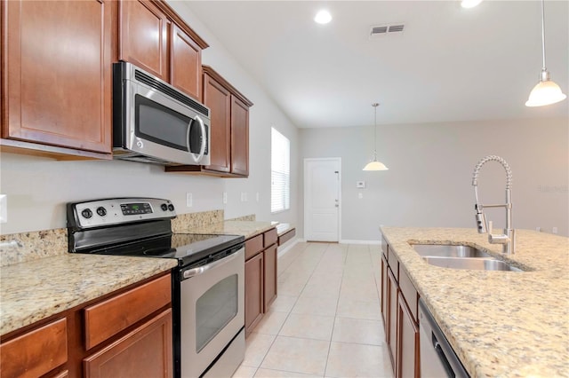 kitchen with light stone countertops, sink, hanging light fixtures, and appliances with stainless steel finishes