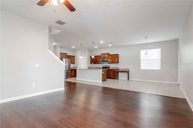 unfurnished living room with hardwood / wood-style floors, ceiling fan, and sink