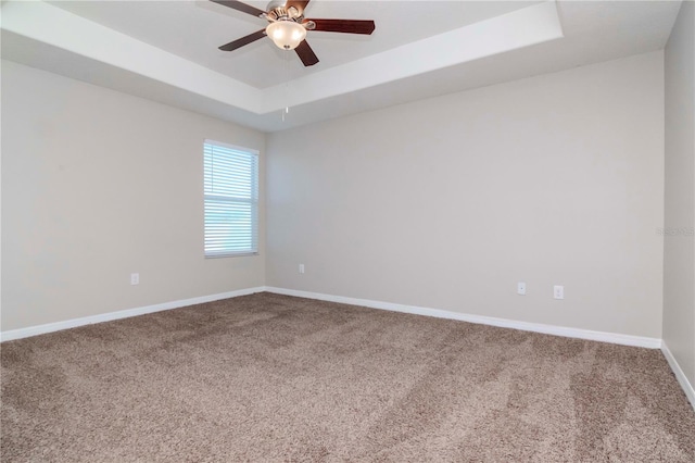 carpeted empty room featuring a tray ceiling and ceiling fan