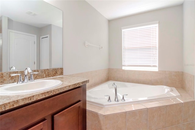 bathroom featuring vanity and a relaxing tiled tub