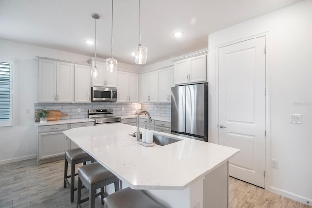 kitchen with a kitchen breakfast bar, a kitchen island with sink, sink, and stainless steel appliances