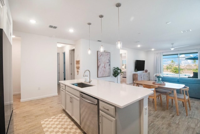 kitchen with dishwasher, sink, hanging light fixtures, a kitchen island with sink, and light wood-type flooring