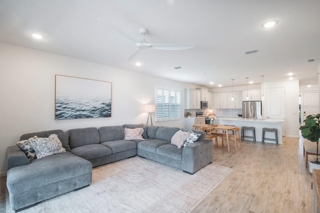 living room featuring ceiling fan and light hardwood / wood-style flooring