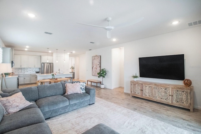 living room with ceiling fan and light hardwood / wood-style flooring