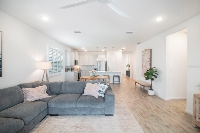 living room featuring ceiling fan and light hardwood / wood-style flooring