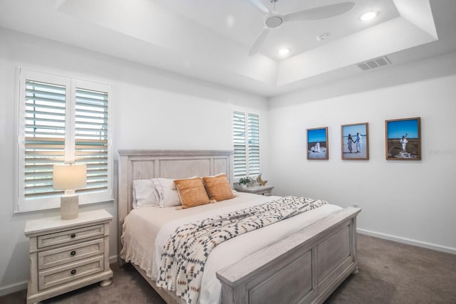 bedroom with a tray ceiling, ceiling fan, and dark carpet