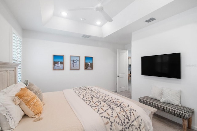 carpeted bedroom with a raised ceiling and ceiling fan