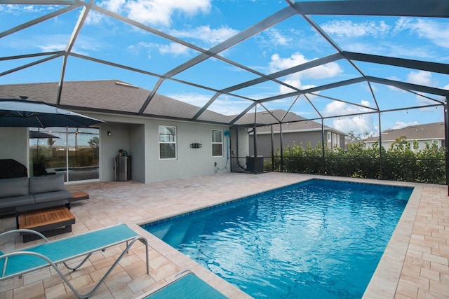 view of swimming pool with glass enclosure, a patio area, and an outdoor living space