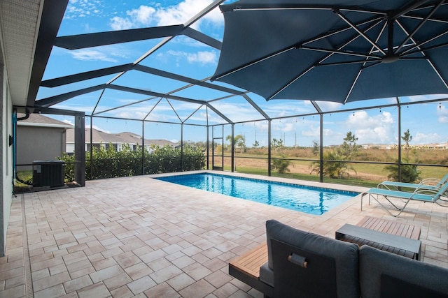 view of swimming pool with glass enclosure, a patio area, and central AC