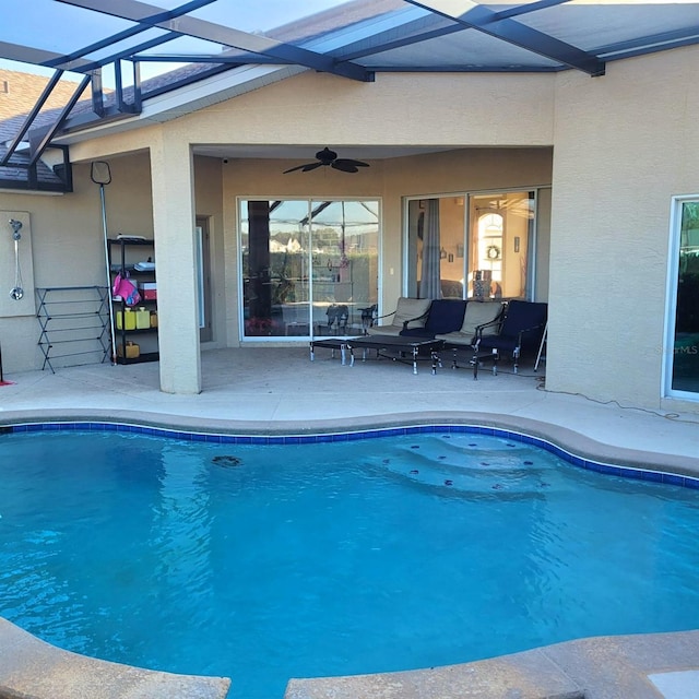 view of swimming pool featuring glass enclosure, ceiling fan, and a patio area