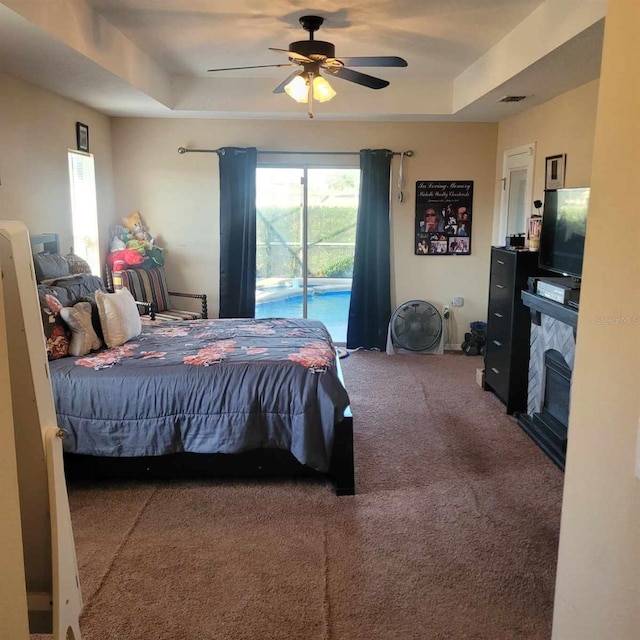 carpeted bedroom featuring access to outside, a raised ceiling, and ceiling fan