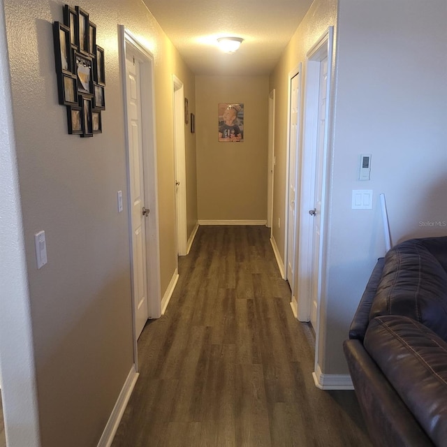 hallway with a textured ceiling and dark wood-type flooring