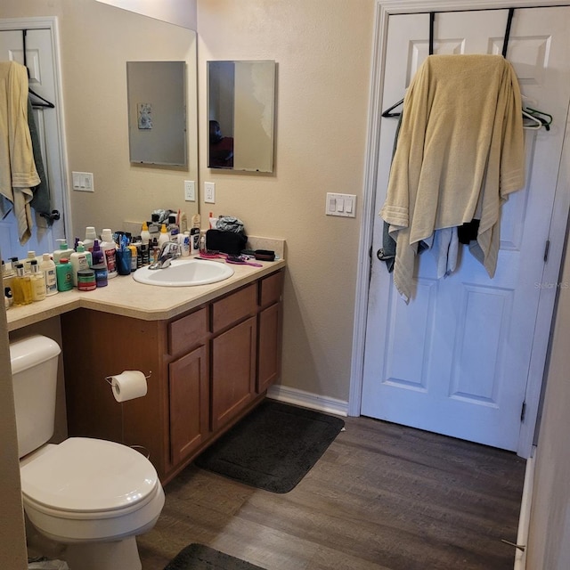 bathroom with hardwood / wood-style floors, vanity, and toilet