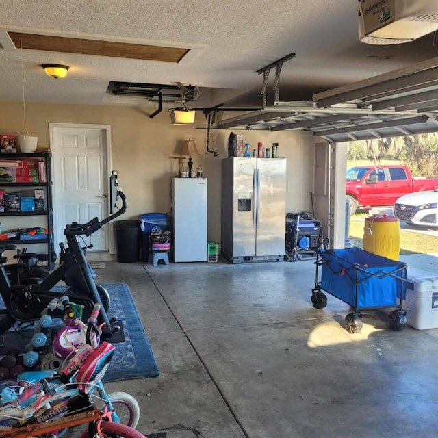 garage featuring stainless steel fridge, white refrigerator, and a garage door opener