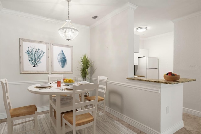 tiled dining room featuring an inviting chandelier and ornamental molding