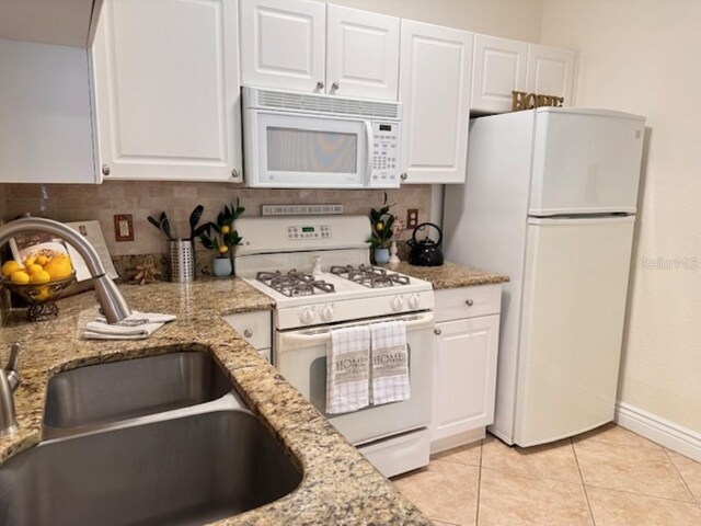 kitchen with white cabinets, white appliances, light stone counters, and sink